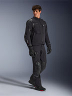 Alpinestars Andes Pro Drystar® XF-jacka, svart och mörkgrå motorcykeljacka, bärs av manlig modell med matchande äventyrsbyxor, handskar och stövlar, helkroppsbild i studio, teknisk äventyrsutrustning för touring med reflexdetaljer och logotyper
