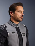 Alpinestars Andes Pro Drystar® XF-jacka, äventyrsjacka för motorcykel, mörkgrå och svart, närbild på bröstparti och krage, med Terra-branding och detalj för vätskerörsledning, bärs av en man i studiomiljö