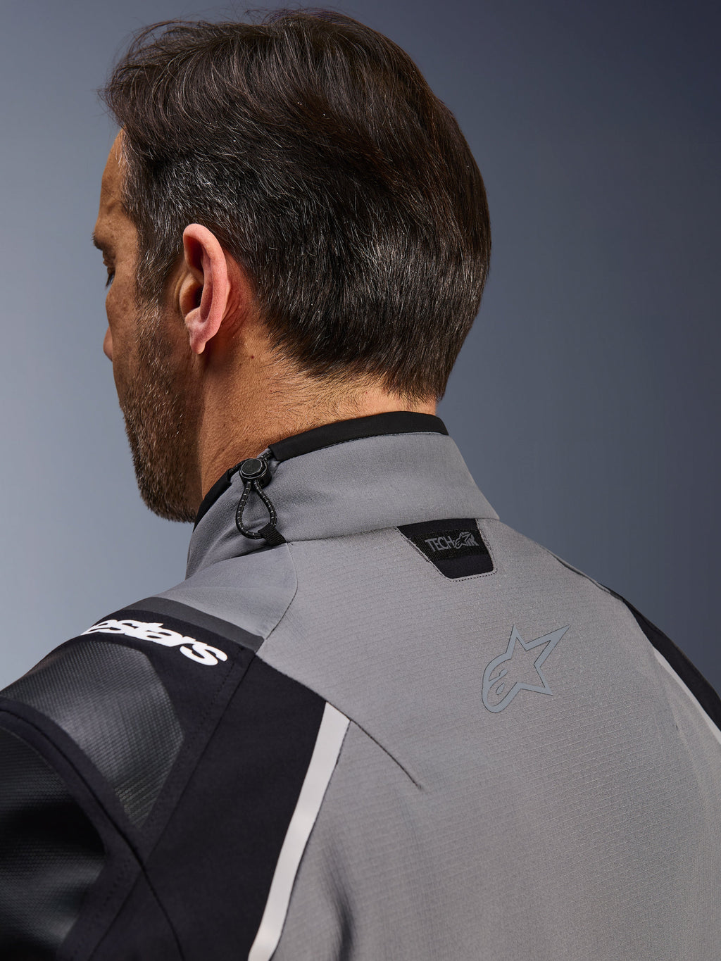 Alpinestars Andes Pro Drystar® XF Jacket, mörkgrå och svart, närbild på den bakre kragen och övre axeln, visar Tech-Air® Ready-logotypen, justering med chocksnodd och ton-i-ton Alpinestars stjärnlogotyp på teknisk textil