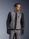 Alpinestars Andes Pro Drystar® XF-jacka i mörkgrått och svart, äventyrsutrustning, bärs av en man med matchande grå byxor och svarta handskar, med ett 3-lagers laminerat skal, praktiska fickor och "Terra"-logotyp på bröstet