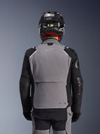 Alpinestars Andes Pro Drystar® XF-jacka, mörkgrå och svart, baksida som visar en stor bakre förvaringsficka och Tech-Air-märkning, bärs av en förare med svart hjälm och matchande mc-byxor, professionell äventyrstouringutrustning