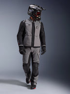 Adventure-förare iklädd Alpinestars Andes Pro Drystar® XF-jacka i mörkgrått och svart, matchande adventure-byxor, svart Alpinestars-hjälm med goggles, svarta handskar och stövlar, komplett teknisk touringutrustning för långdistanskörning