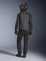 Alpinestars Cusco Drystar® jacka, svart och djupgrå, ryggvy av förare som bär komplett adventure touring-utrustning, stor grå ryggpanel med Alpinestars-logotyp, blå detaljer på ärmarna, bärs med matchande svarta byxor och hjälm.