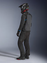 Motorcyklist som bär Alpinestars Cusco Drystar®-jacka i Black och Deep Gray med blå detaljer, svarta körbyxor, kolfiber SM10-hjälm och svarta handskar, vy bakifrån som visar den stora ventilationspanelen och adventure touring-designen.