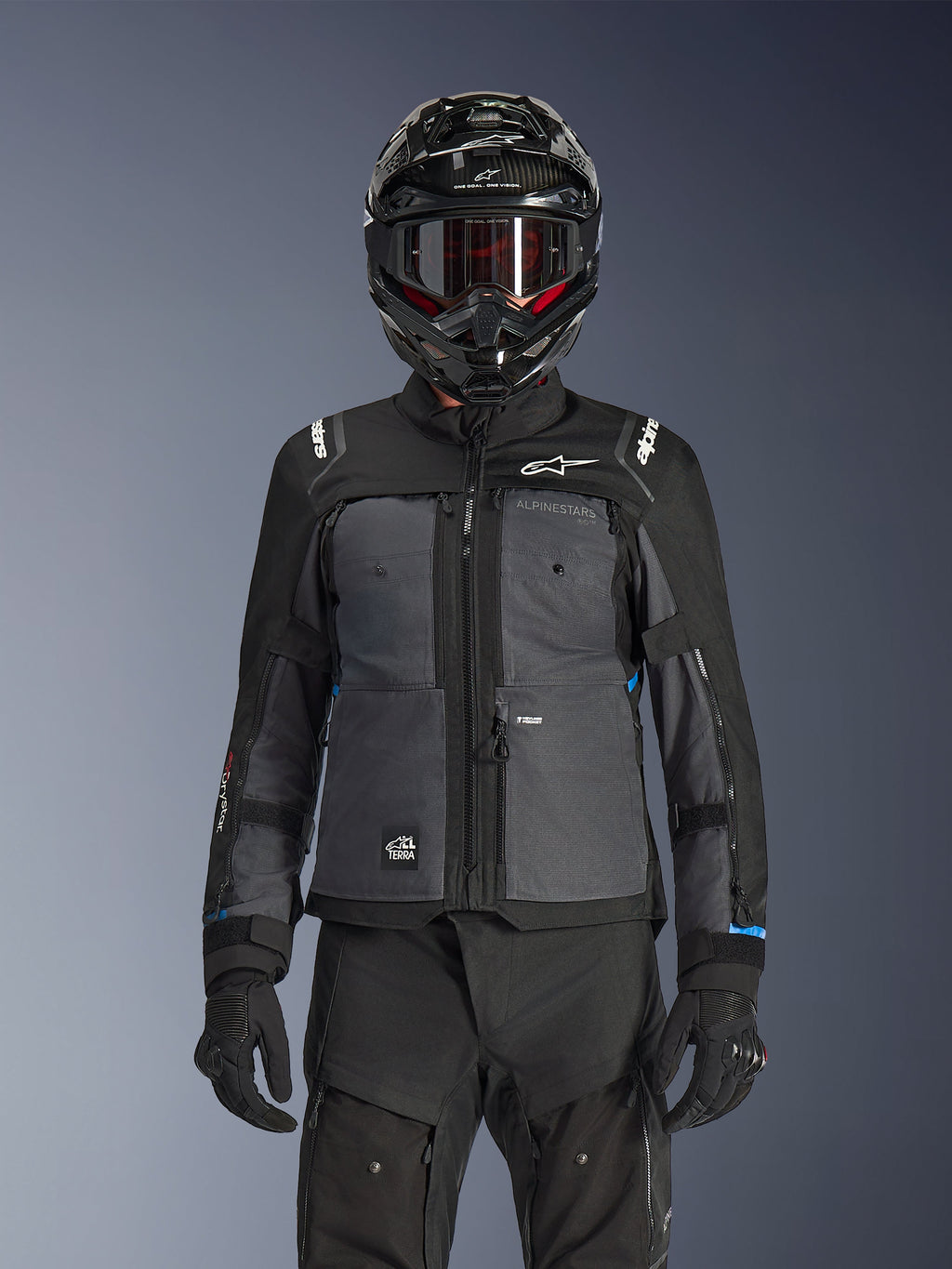 Alpinestars Cusco Drystar® jacka, svart och mörkgrå, adventure touring-jacka för motorcykel bärs med matchande svarta tekniska byxor och en dual-sport-hjälm, med en tvåtonsdesign, ripstop-paneler och Alpinestars-logotyp