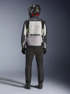 Motorcykelförare sedd bakifrån iklädd Alpinestars Cusco Drystar®-jacka i Ice Gray, Mid Gray och Deep Gray, med en stor ventilationspanel på ryggen och Alpinestars-logotyp, kombinerad med svarta körbyxor och en svart hjälm, adventure touring-motorcykelkläder.