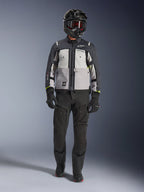 Alpinestars Cusco Drystar®-jacka, Ice Gray Mid Gray Deep Gray, äventyrsmotorcykeljacka som bärs med svarta MC-byxor, svarta handskar och en svart hjälm med goggles, med färgblockerade grå paneler och tekniska detaljer för väg- och äventyrstouring.
