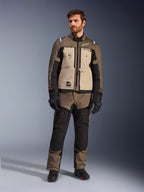 Alpinestars Cusco Drystar®-jacka i Walnut Aluminum Black, bärs av en manlig förare med matchande adventure touring-byxor, svarta handskar och stövlar, med beigea bröstpaneler, svarta ärmar med subtila orangea detaljer och funktionella ventilationsdragkedjor för landsvägskörning.