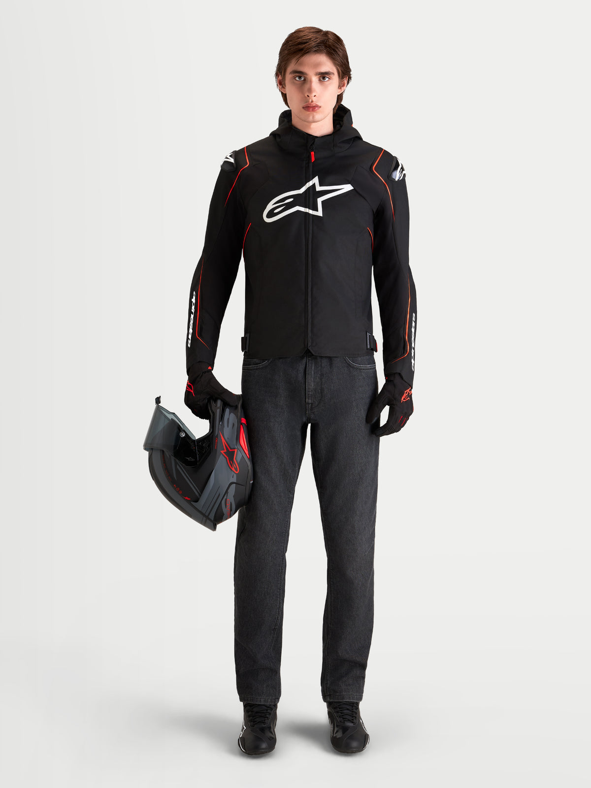 Alpinestars Zaca V2 Waterproof jacka, svart och röd sportmotorcykeljacka för herr med DFS-axelskydd och integrerad huva, bärs av modell som håller en hjälm