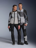 Manlig och kvinnlig modell bär Alpinestars ST-2 Air-jackor i Ice Gray, Dark Gray och Black, teknisk motorcykelutrustning för sommarturer med stora meshpaneler och exploration equipment-märkning, matchat med svarta körbyxor, handskar och stövlar.