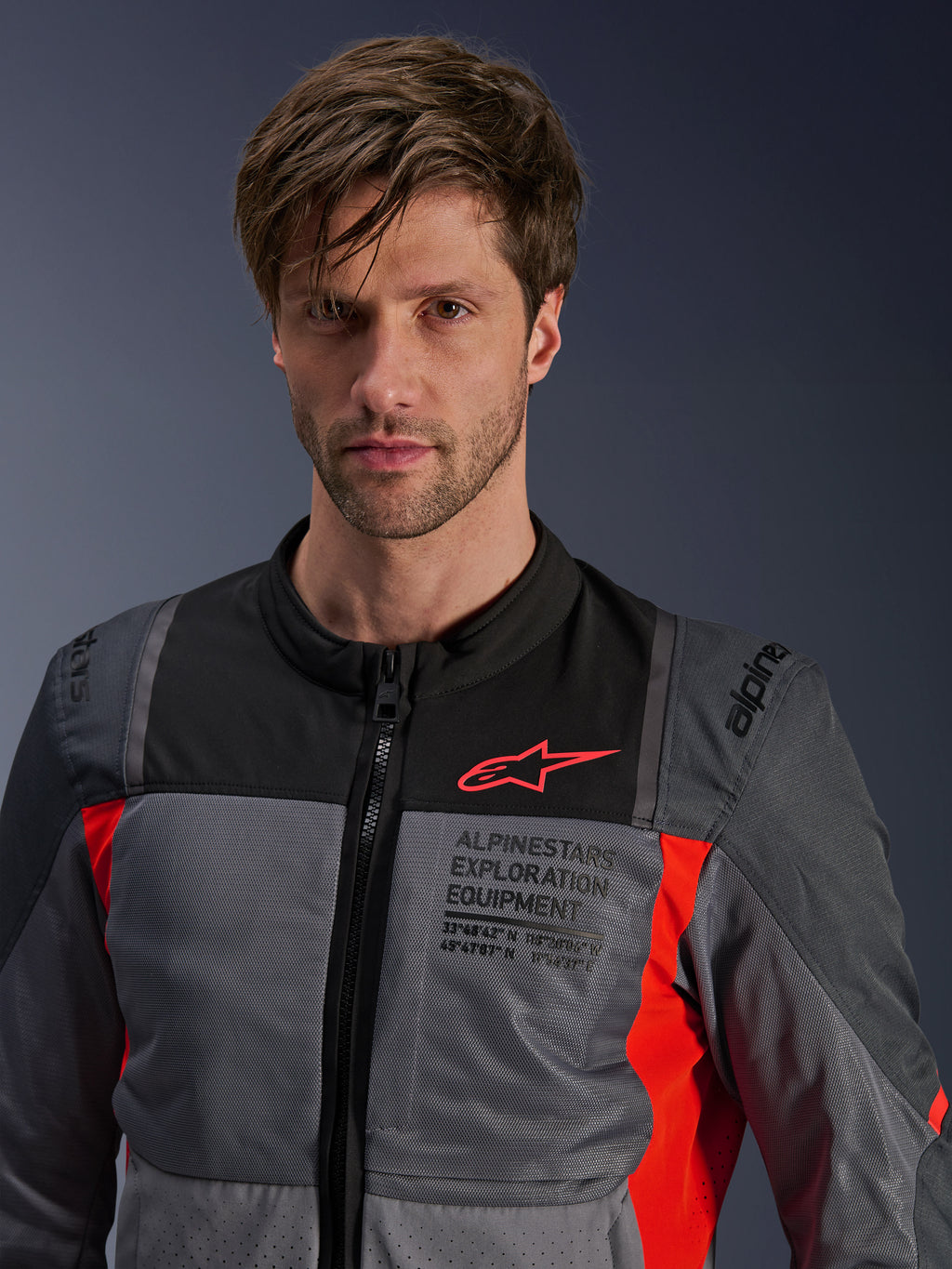 Alpinestars ST-2 Air Jacket, Deep Gray Dark Gray and Bright Red, summer touring motorcycle jacket worn by a model, featuring mesh ventilation panels, red Astars logo, and 'Exploration Equipment' branding on the chest.