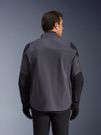 Alpinestars Maxdura Drystar®XF Laminated Armored Shell, teknisk äventyrsjacka, mörkgrå och svart, baksida med förstärkta axel- och armbågspaneler, diskret logotyp på övre delen av ryggen, buren med svarta handskar och byxor, konstruerad för skydd i alla väder