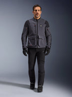 Maxdura Drystar®XF Laminated Armored Shell, motorcykeljacka, Deep Gray Black, bärs av en modell med svarta byxor och handskar, med stora utanpåfickor, röda dragkedjedetaljer och All Terra-branding, teknisk utrustning för äventyrskörning