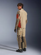 Manlig modell iklädd Alpinestars Maxdura Drystar®XF Laminated Armored Shell i Aluminum Walnut Rust Brown, matchande adventure touring-byxor, svarta handskar och svarta stövlar, vy bakifrån som visar den tekniska textilkonstruktionen och förstärkta zoner.