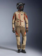 Helkroppsbild i studio av en förare iklädd Alpinestars Maxdura Drystar®XF Laminated Armored Shell-jacka i Aluminum Walnut Rust Brown, matchad med tillhörande äventyrsbyxor, en svart offroad-hjälm med rödtonade goggles och tekniska handskar, som visar en komplett outfit för äventyrstouring.