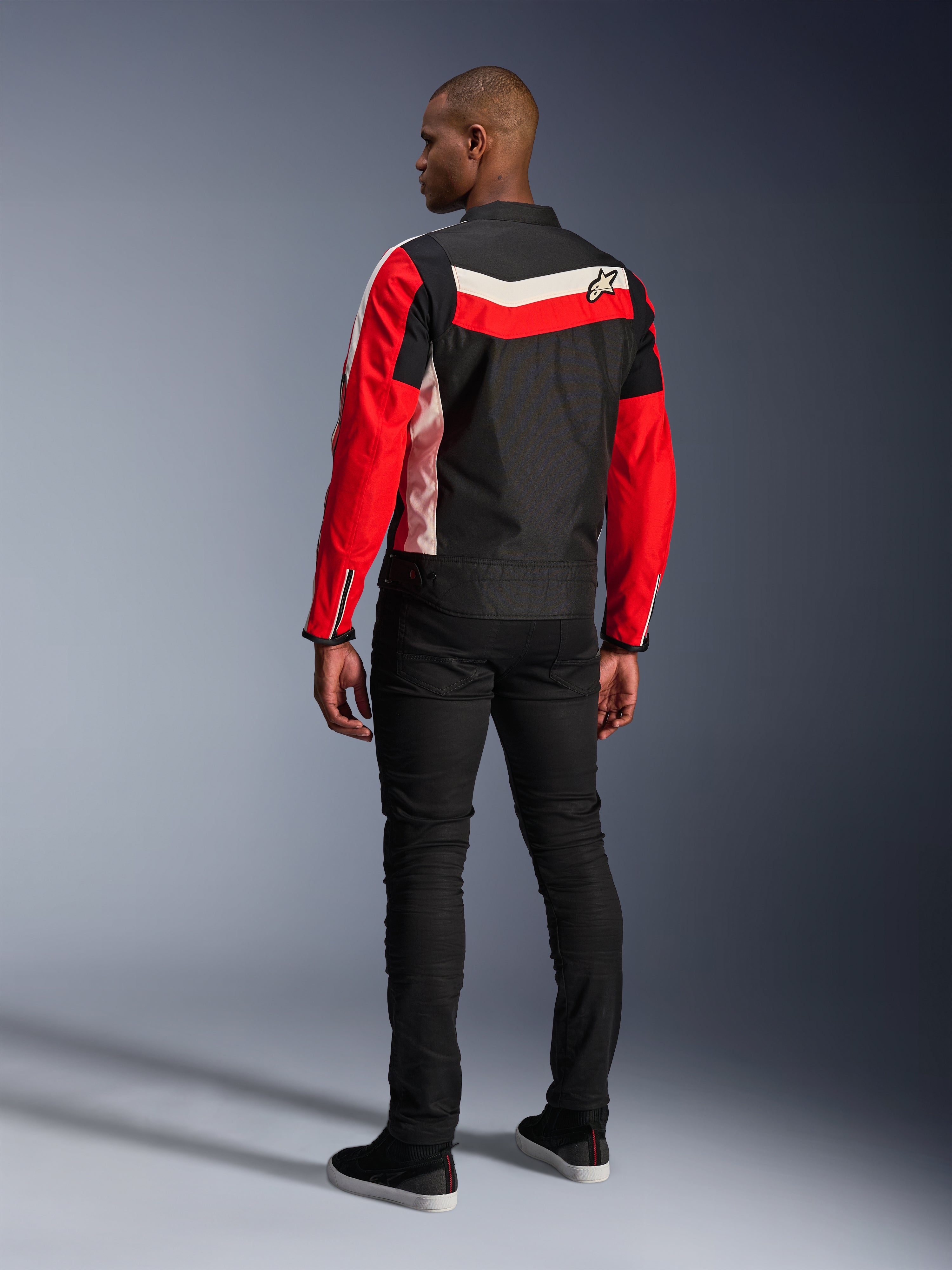 Alpinestars T-Dyno WR-jacka, motorcykeljacka i textil, svart, klarröd och ecru, ryggvy på modell, vintageinspirerad biker-passform med färgpaneler och logotyp i heritage-stil, modern urban utrustning för vägkörning.