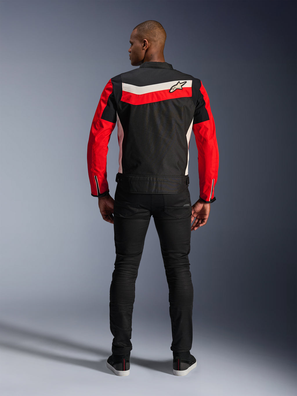 Alpinestars T-Dyno WR-jacka, textiljacka för motorcykel, svart, klarröd och ecru, vy bakifrån som visar horisontella ränder på ryggen och röda ärmar, vintageinspirerad biker-passform, buren med svarta byxor, urban mc-utrustning