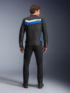 Alpinestars T-Dyno WR Jacket, motorcykeljacka i textil, färgkombinationen Black Blue Ecru, hel ryggvy på modell, med ett blått och off-white chevron-format band med Alpinestars-logotyp, kombinerad med svarta byxor och stövlar, vintageinspirerad urban mc-utrustning