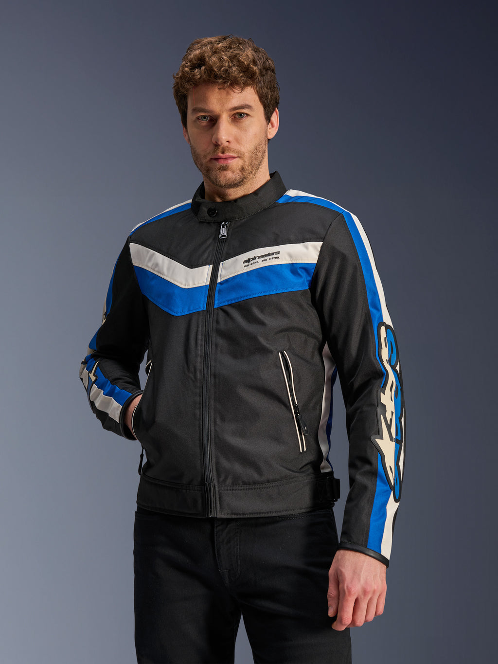 Alpinestars T-Dyno WR-jacka i Black Blue Ecru, motorcykeljacka i textil med blå och benvita chevron-ränder på bröstet och ärmarna, buren av en modell.