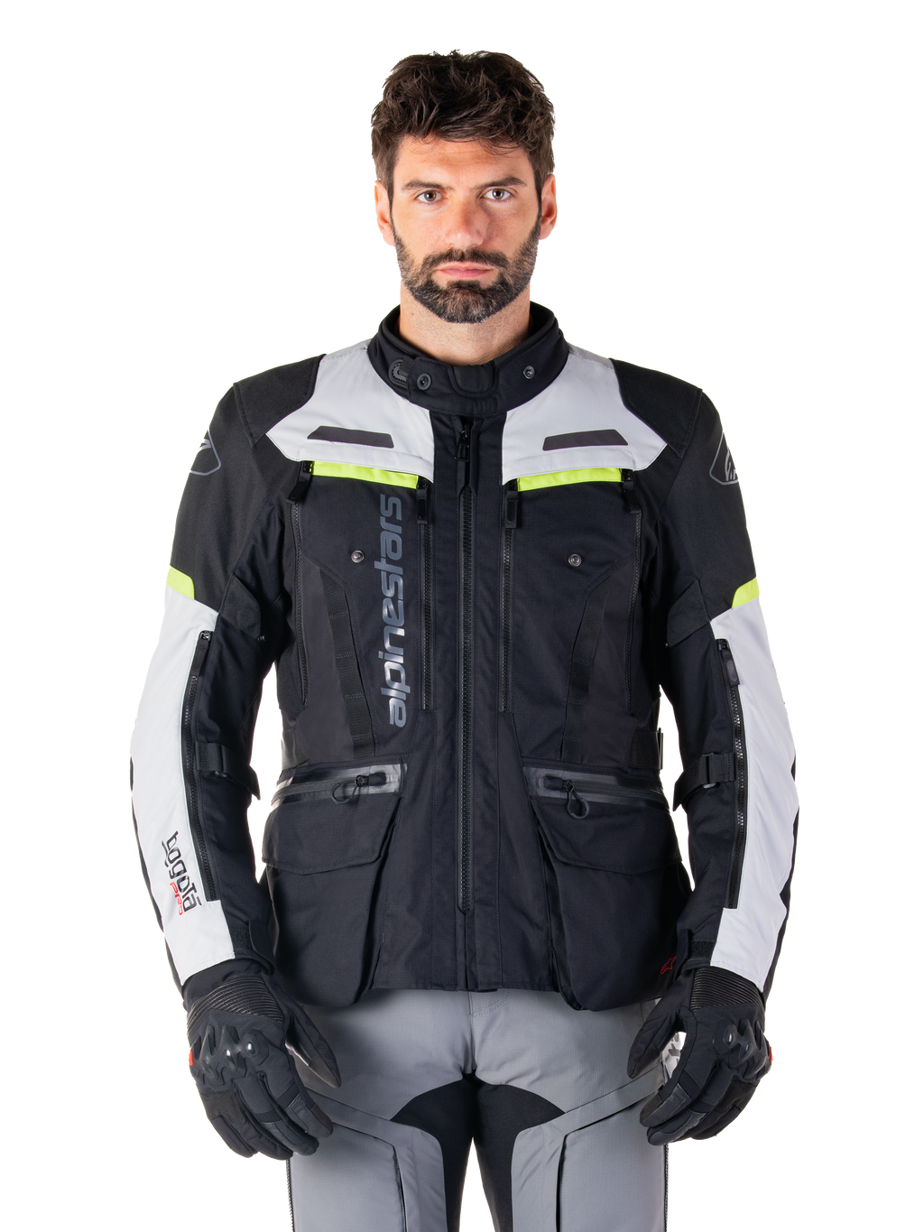 Man som bär Alpinestars Bogotá Pro Drystar®-jacka i färgerna svart, isgrå och neongul, allväders motorcykeljacka för adventure-touring, vattentät design med flera fickor och vertikal logotyp, matchad med svarta handskar och grå körbyxor