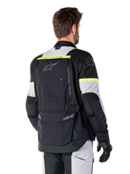 Alpinestars Bogotá Pro Drystar®-jacka, adventure touring-jacka, Black Ice Gray och Yellow Fluo, vy bakifrån med stor ryggficka med 'TECH TOURING'-logotyp, Alpinestars-logotyp och fluorescerande detaljer, teknisk mc-utrustning i textil