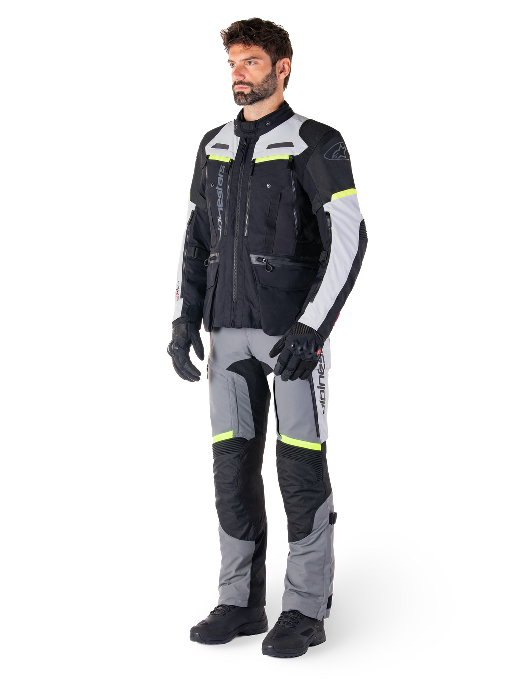 Alpinestars Bogotá Pro Drystar®-jacka, motorcykeljacka för adventure touring, Black Ice Gray Yellow Fluo, bärs av modell med matchande byxor och svarta handskar, med vattentät textilkonstruktion, ventilationspaneler och fluorescerande detaljer.