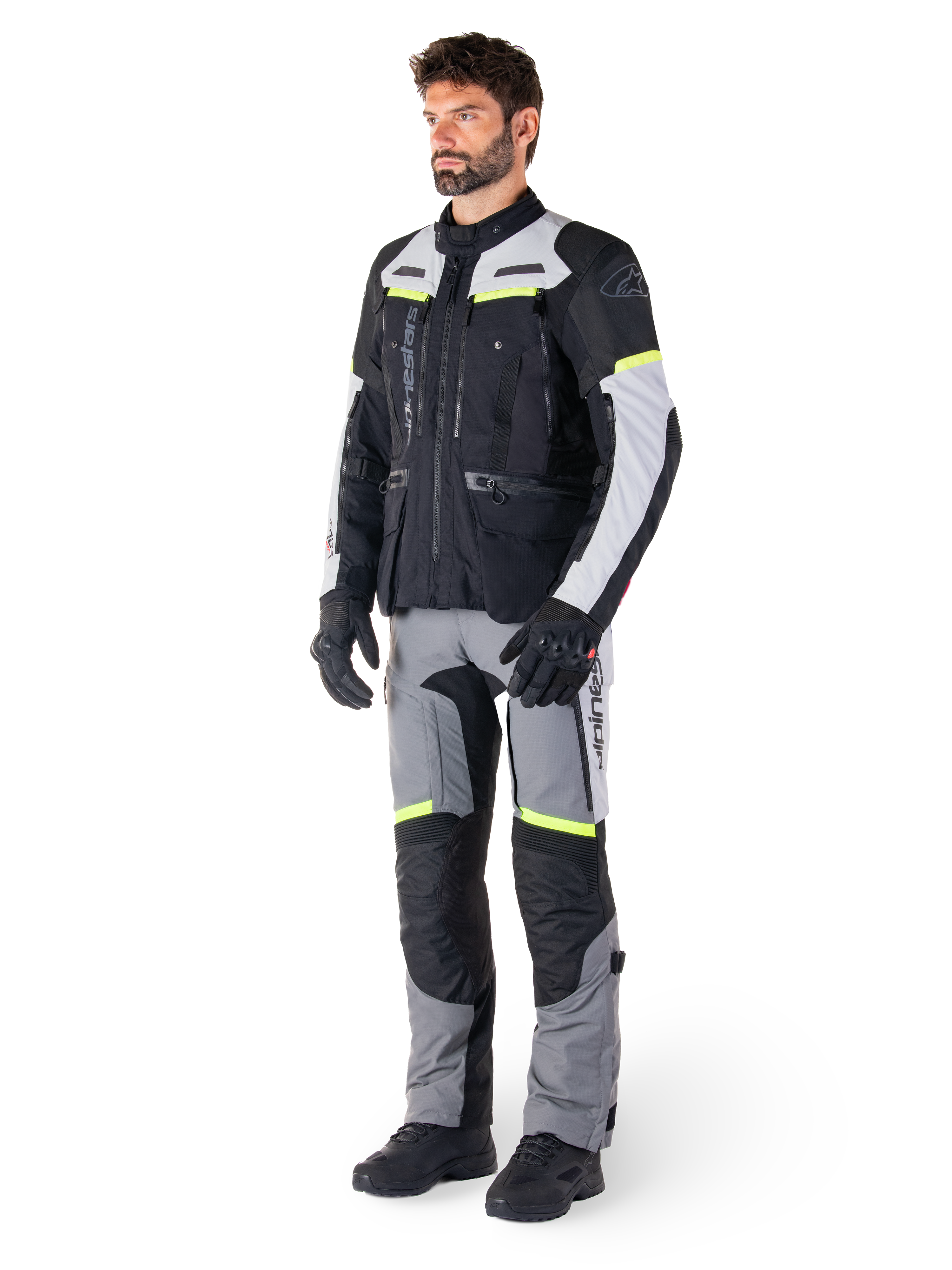Alpinestars Bogotá Pro Drystar®-jacka, motorcykeljacka för adventure touring, Black Ice Gray Yellow Fluo, bärs av modell med matchande byxor och svarta handskar, med vattentät textilkonstruktion, ventilationspaneler och fluorescerande detaljer.
