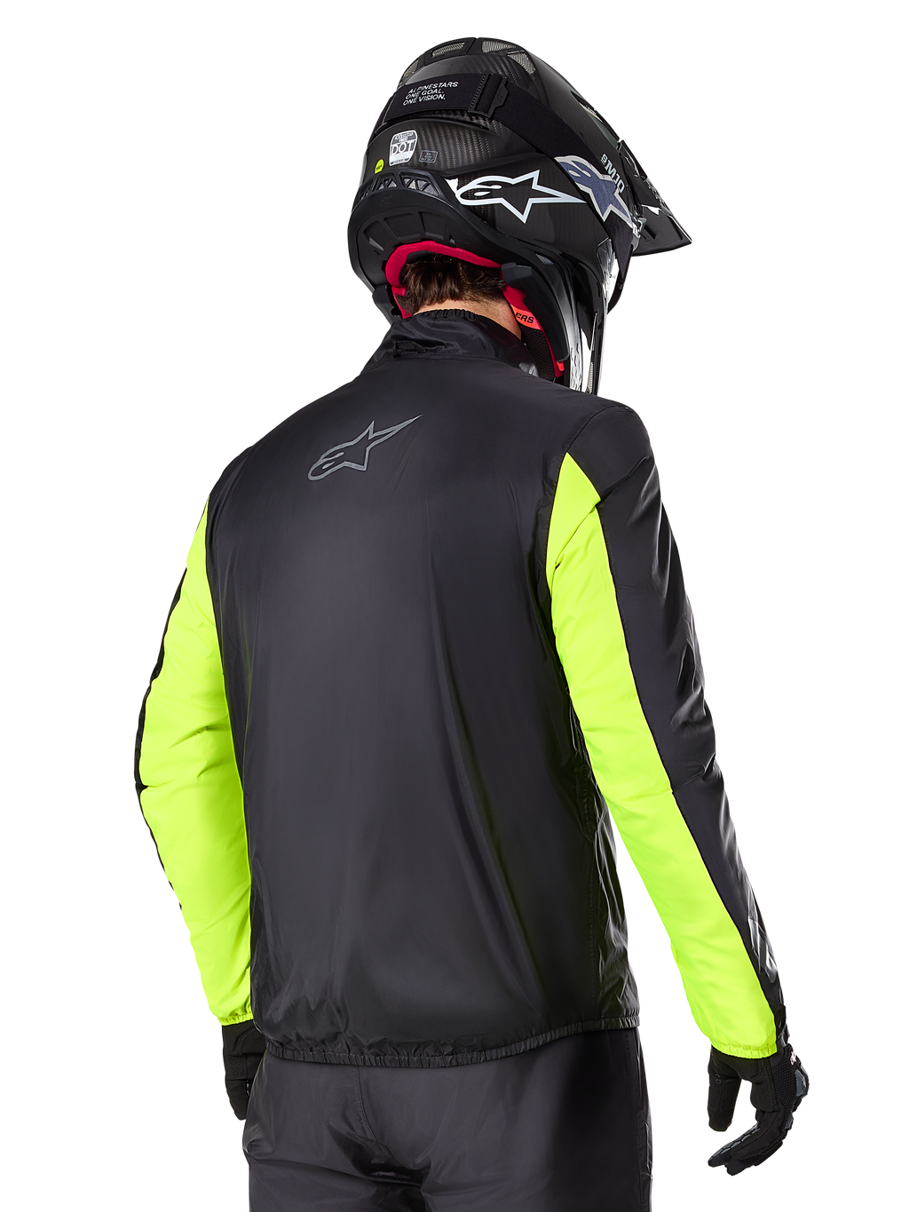 Alpinestars Bogotá Pro Drystar®-jacka, vy bakifrån, svart med gul fluo-ärmar, bärs av en förare med svart hjälm och handskar, hög synlighet motorcykelutrustning för äventyrstouring med teknisk textilfinish.