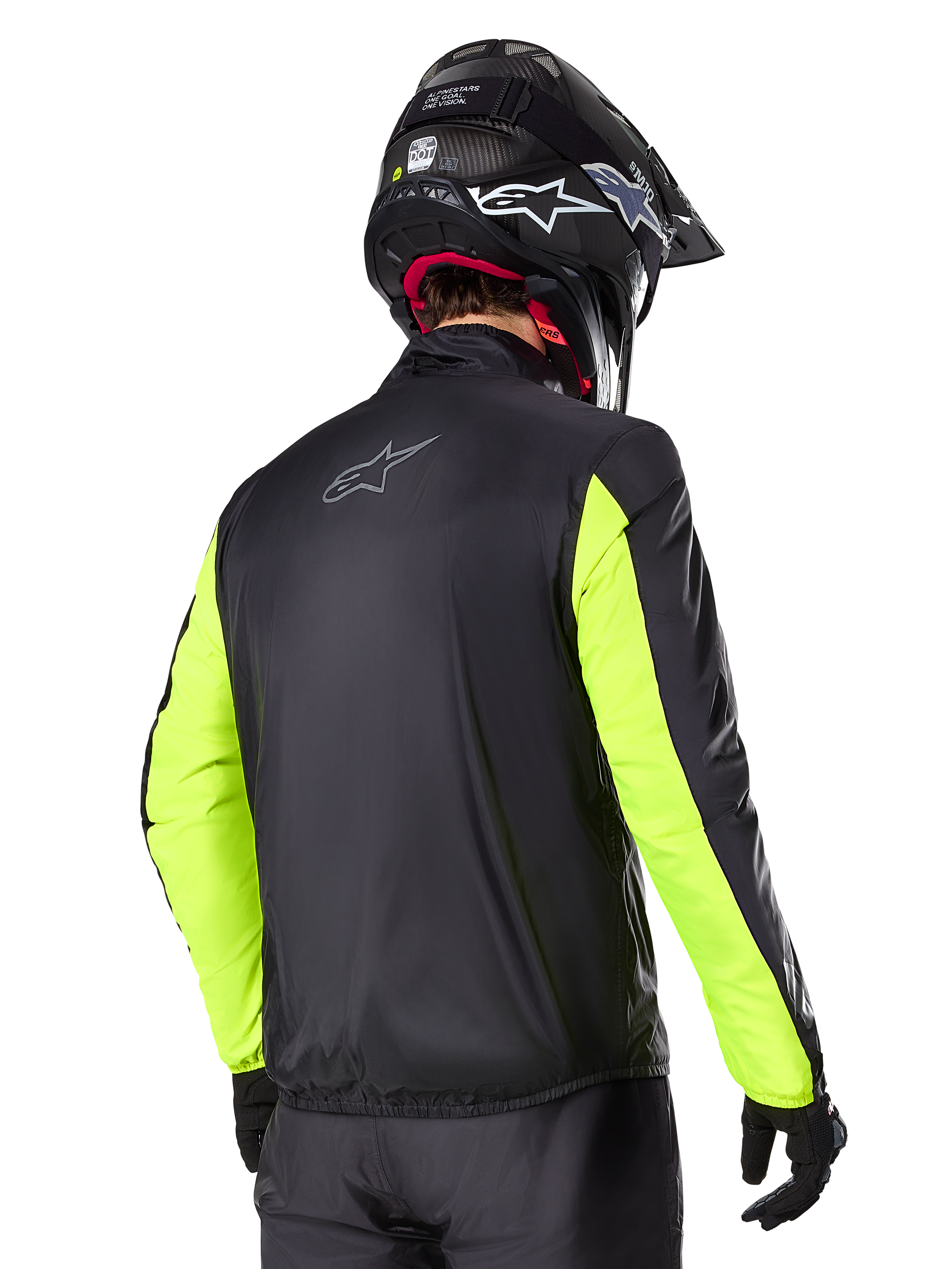 Alpinestars Bogotá Pro Drystar®-jacka, vy bakifrån, svart med gul fluo-ärmar, bärs av en förare med svart hjälm och handskar, hög synlighet motorcykelutrustning för äventyrstouring med teknisk textilfinish.