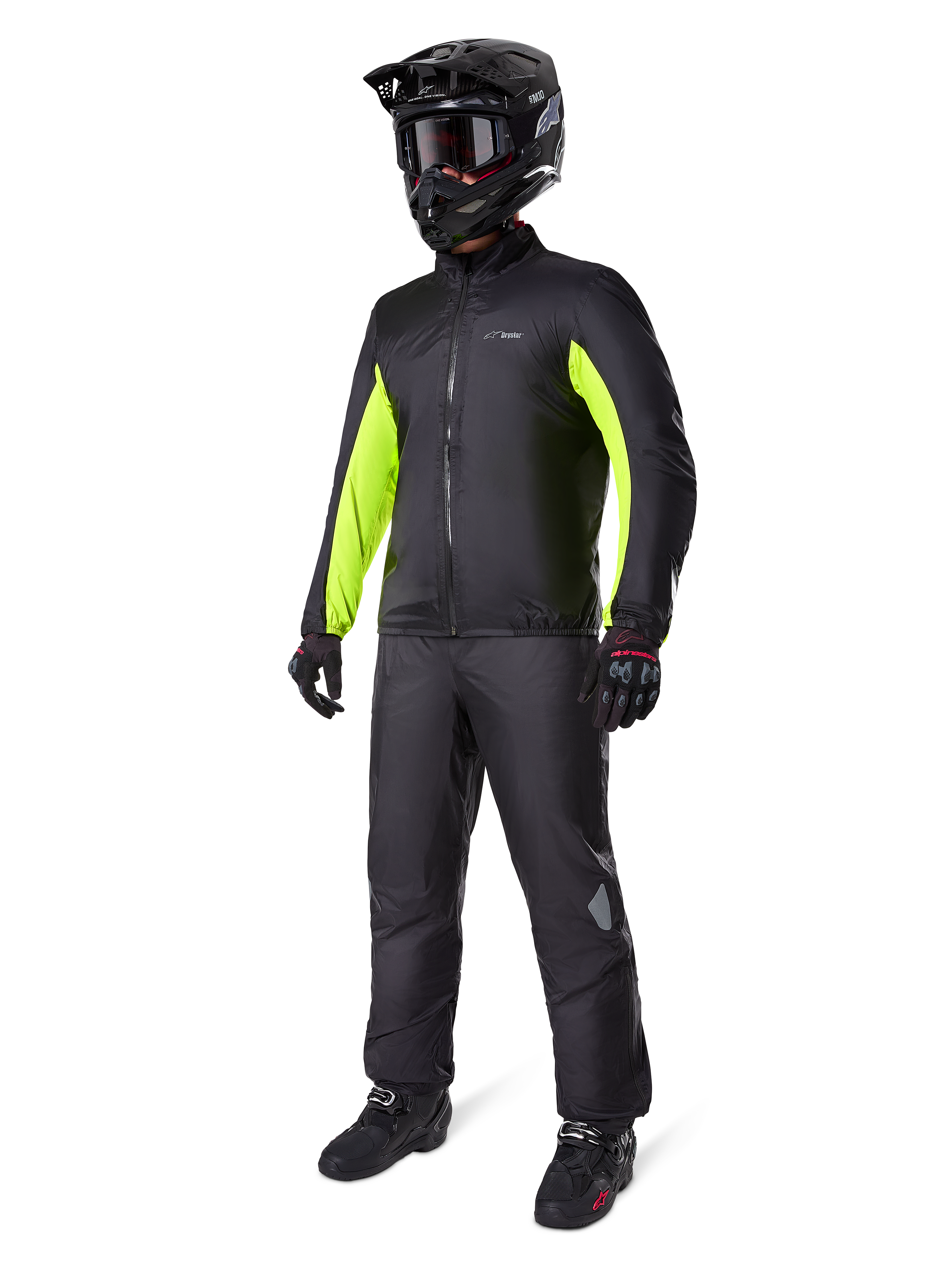 Motorcyklist klädd i Alpinestars Bogotá Pro Drystar®-jackfoder, svart med lysande Yellow Fluo-paneler på ärmarna, matchande svarta byxor, svart motocrosshjälm och handskar, vattentät äventyrsutrustning för alla säsonger