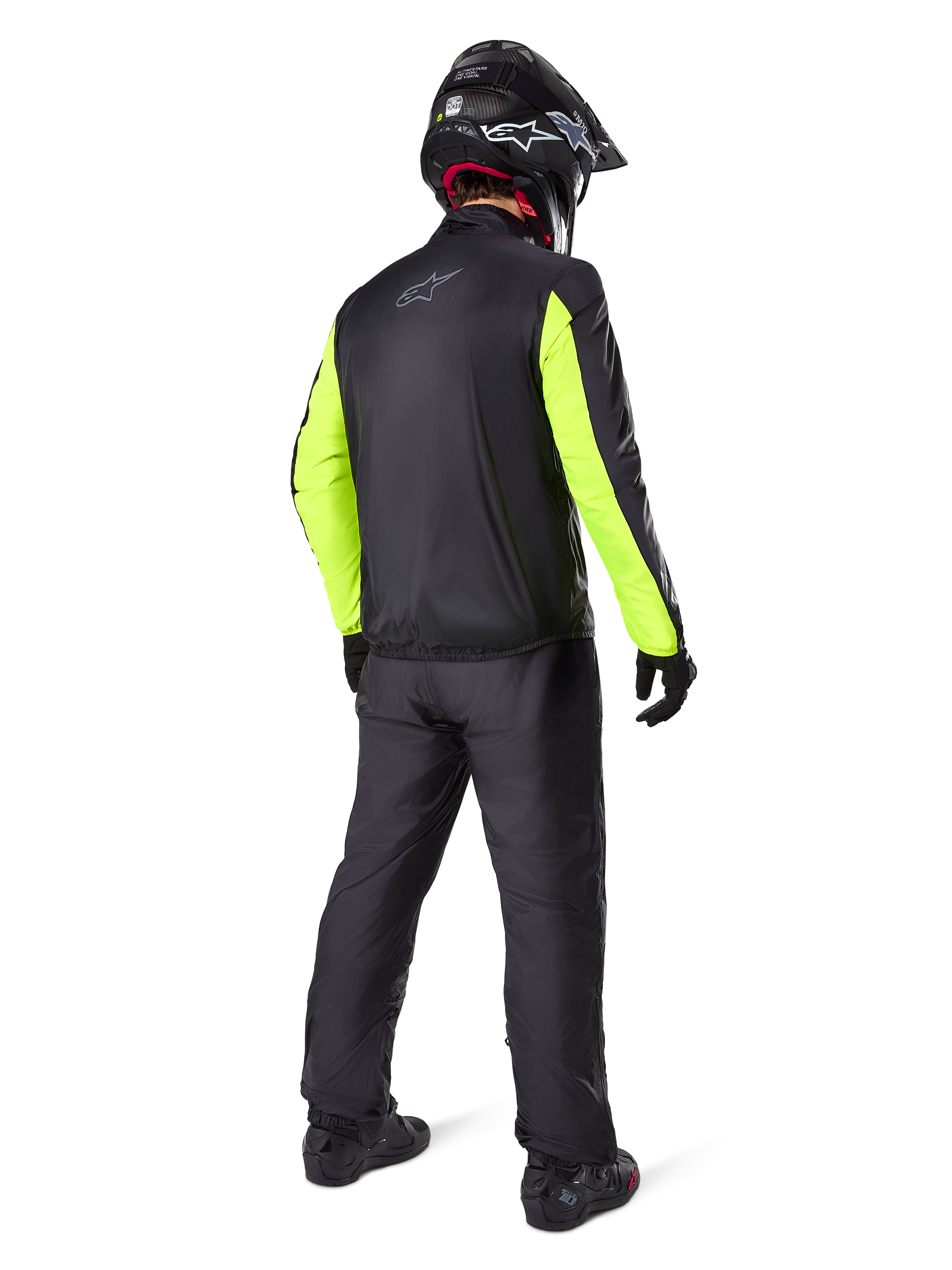 Motorcyklist sedd bakifrån i Alpinestars Bogotá Pro Drystar®-jacka, svart med lysande gula fluo-ärmar, matchande svarta byxor och hjälm, teknisk äventyrsutrustning för alla säsonger