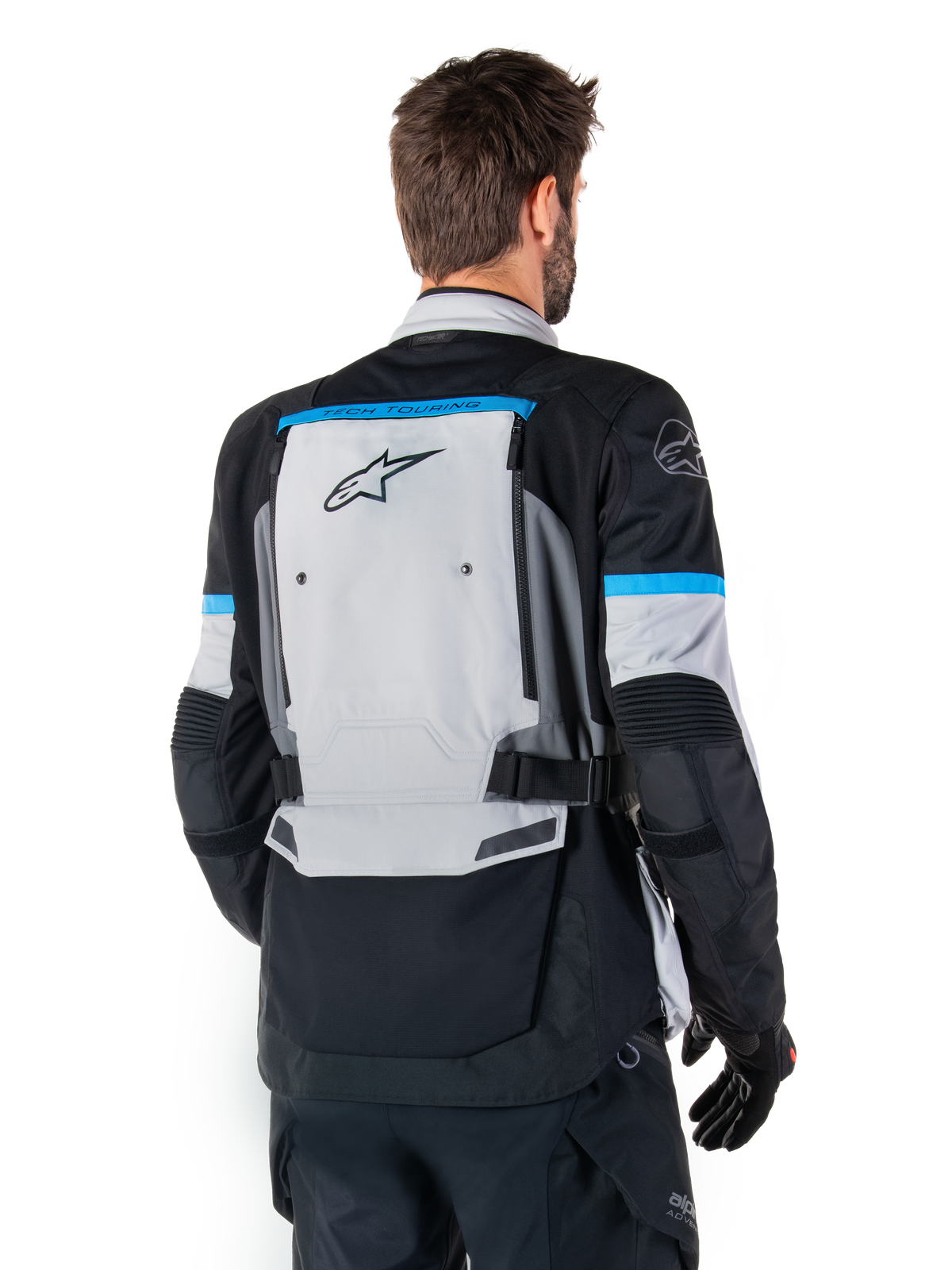 Alpinestars Bogota' Pro Drystar®-jacka, äventyrsmotorcykeljacka, Ice Gray, svart och cyan, ryggvy som framhäver den stora grå ryggpanelen med Tech Touring-branding, cyanfärgade detaljer på ärmarna och slitstark textilkonstruktion.