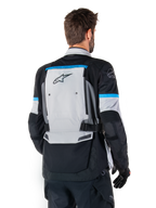 Alpinestars Bogota' Pro Drystar®-jacka, äventyrsmotorcykeljacka, Ice Gray, svart och cyan, ryggvy som framhäver den stora grå ryggpanelen med Tech Touring-branding, cyanfärgade detaljer på ärmarna och slitstark textilkonstruktion.