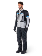 Manlig förare i Alpinestars Bogotá Pro Drystar®-jacka i Ice Gray, svart och cyan, matchad med svarta tekniska körbyxor och handskar, äventyrstouringutrustning för prestanda i alla väder