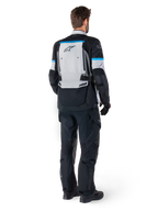 Alpinestars Bogota' Pro Drystar® jacka, äventyrsmotorcykeljacka, isgrå, svart och cyan, sedd bakifrån buren med matchande svarta byxor och handskar, med en stor grå ryggpanel med svart Alpinestars-logotyp och cyanblå accenter.