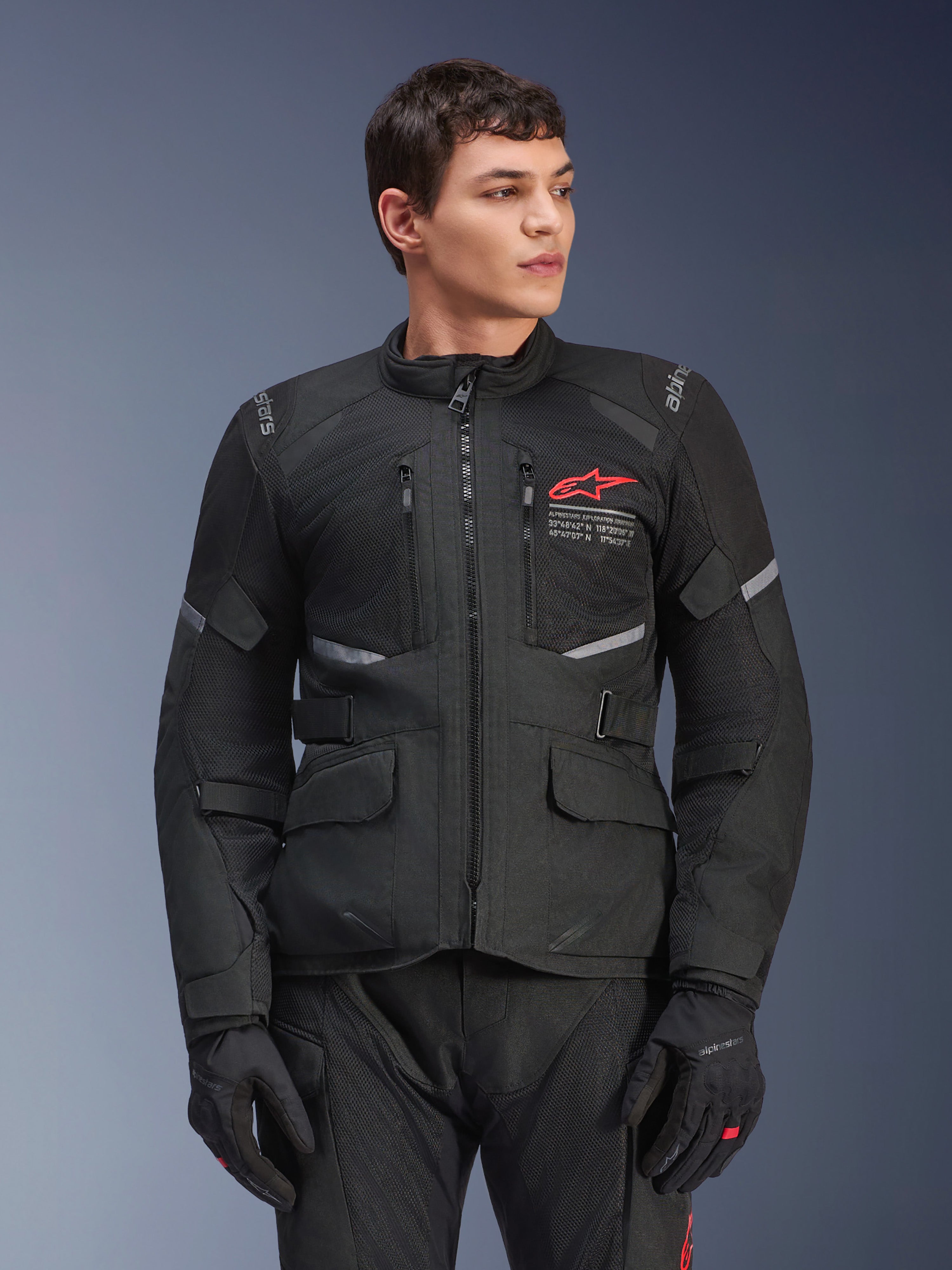 Alpinestars Andes Air Drystar® jacka, svart motorcykeltouringjacka, röd stjärnlogotyp på bröstet, med ventilationspaneler i mesh och reflekterande detaljer, bärs av manlig modell med svarta körhandskar, äventyrsutrustning för två säsonger