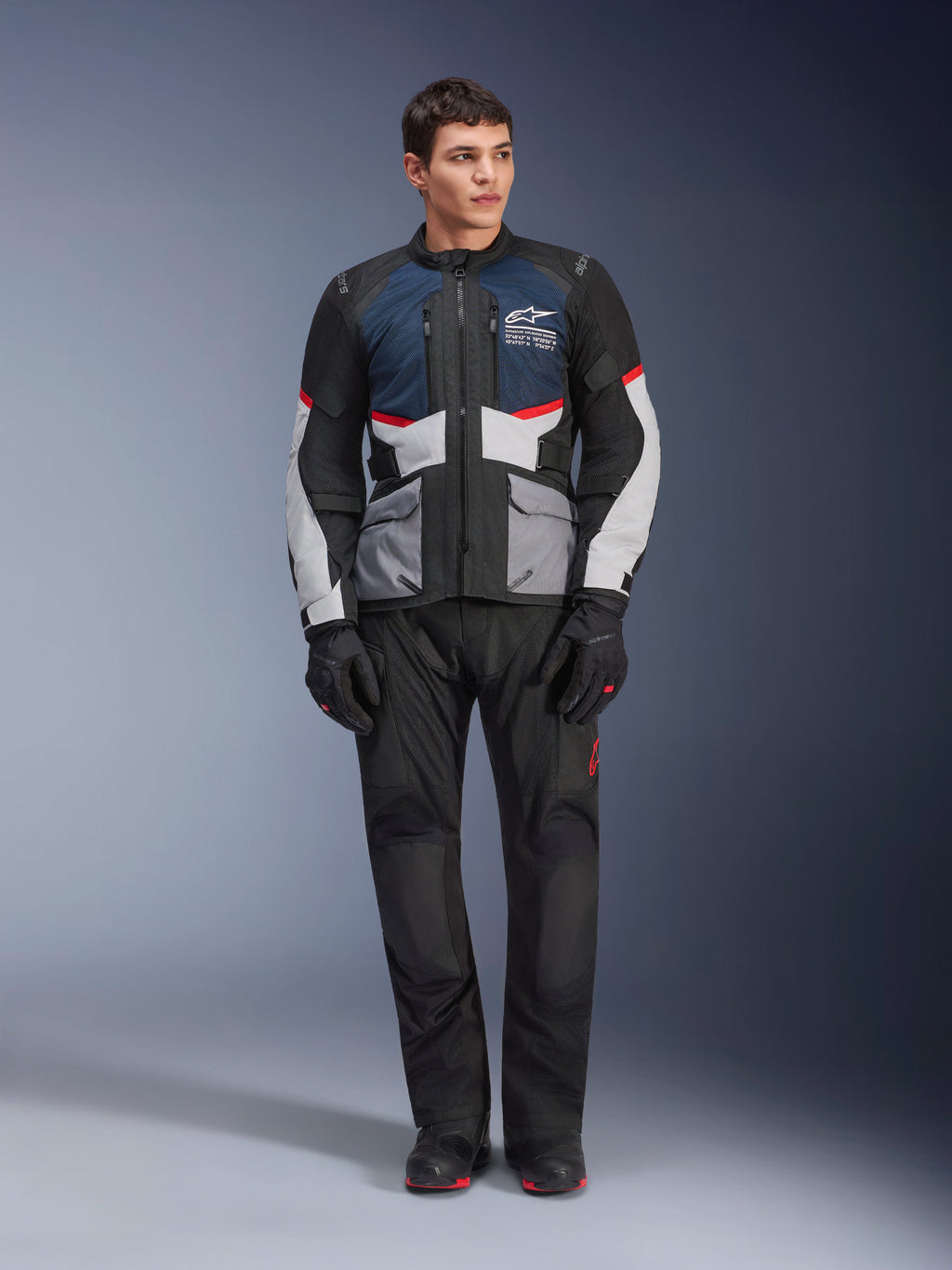 Alpinestars Andes Air Drystar®-jacka, touringjacka för motorcykel, mörkblå, svart och isgrå, buren med matchande svarta adventure-byxor och handskar, med nätpaneler för luftflöde och en teknisk design med flera fickor.