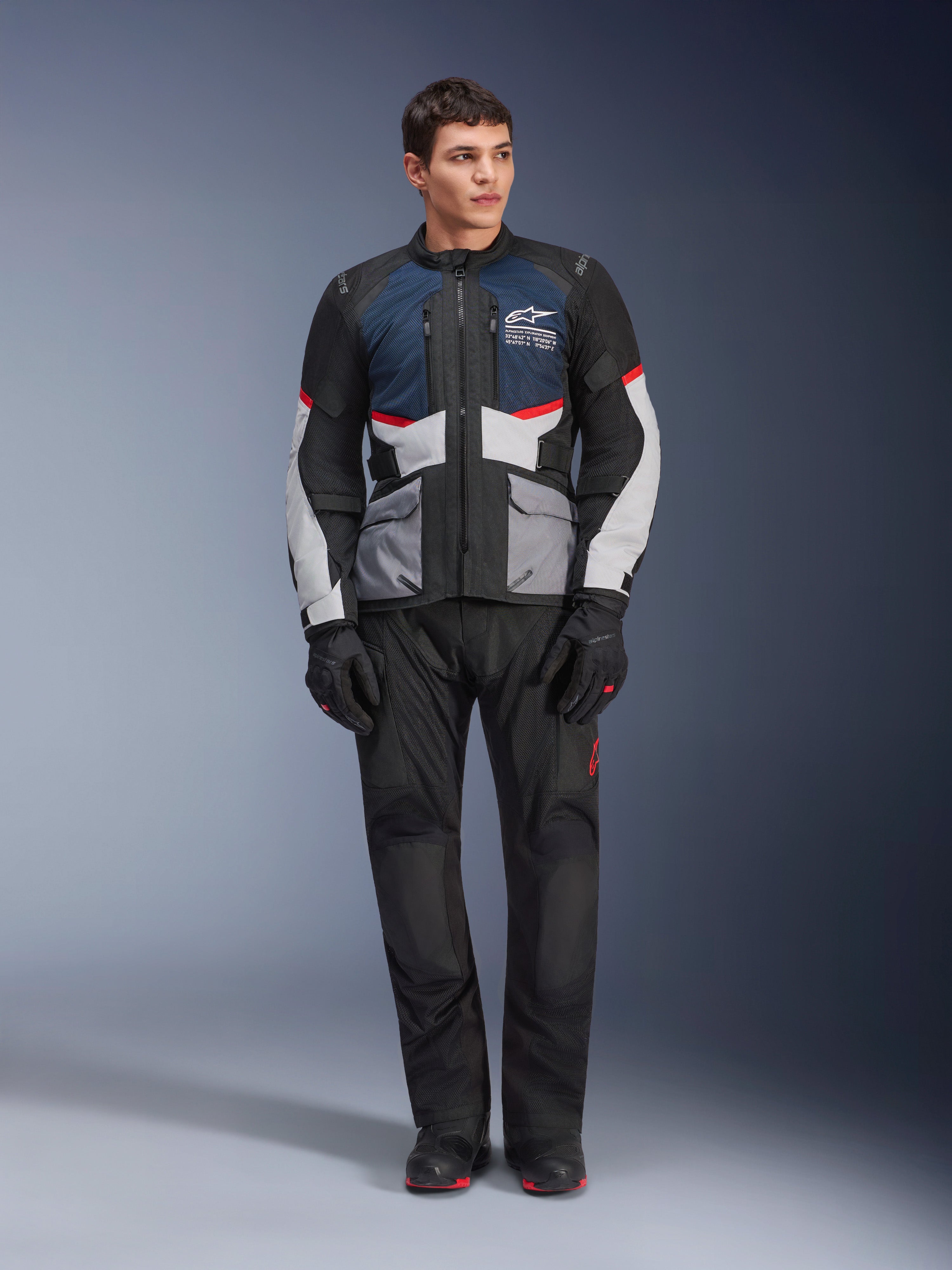 Alpinestars Andes Air Drystar®-jacka, touringjacka för motorcykel, mörkblå, svart och isgrå, buren med matchande svarta adventure-byxor och handskar, med nätpaneler för luftflöde och en teknisk design med flera fickor.