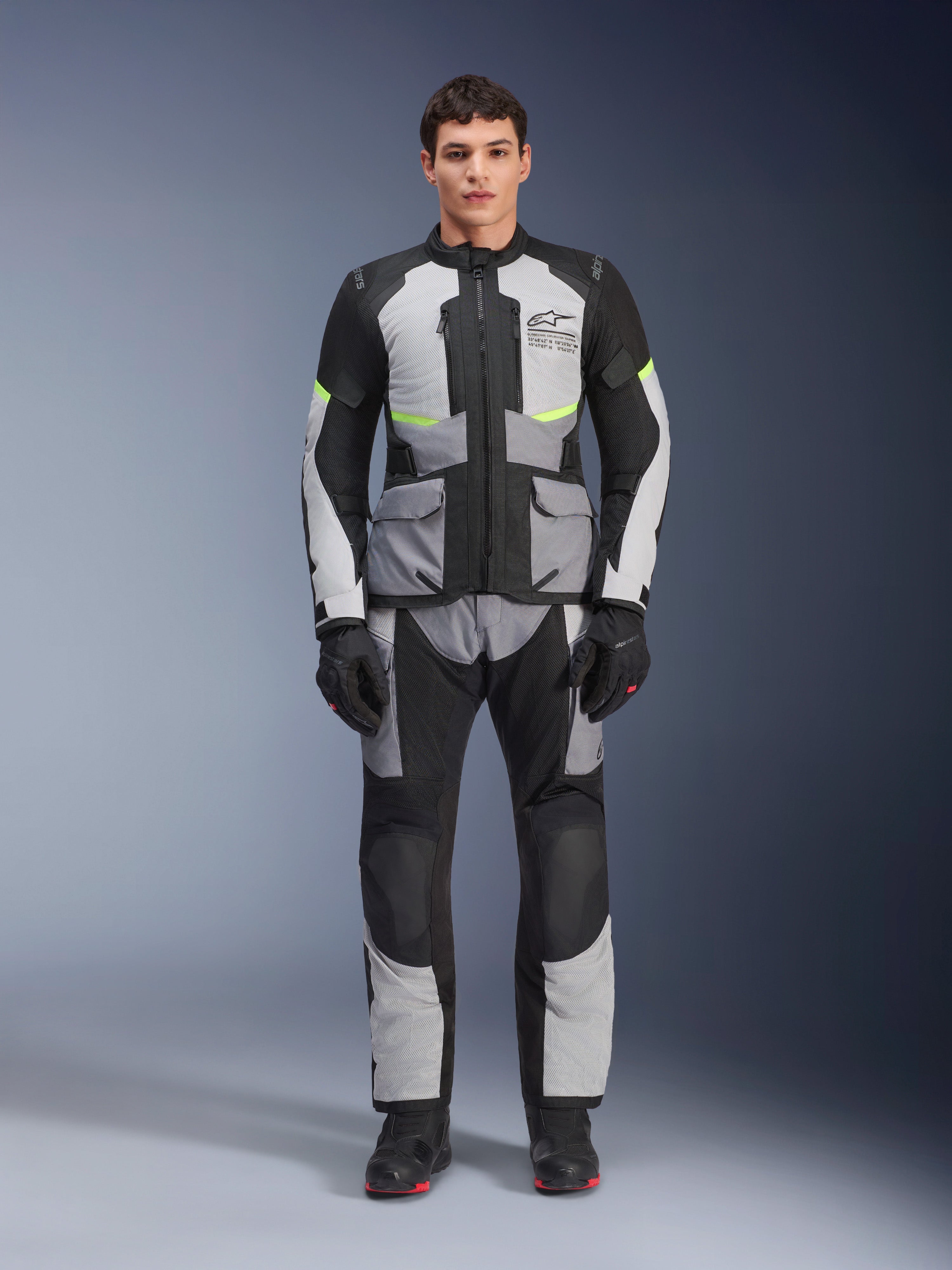 Alpinestars Andes Air Drystar®-byxor, motorcykelbyxor för adventure touring, isgrå och svarta med neongula detaljer, helbild på en modell som bär matchande jacka och handskar, textildesign med ventilationspaneler i mesh