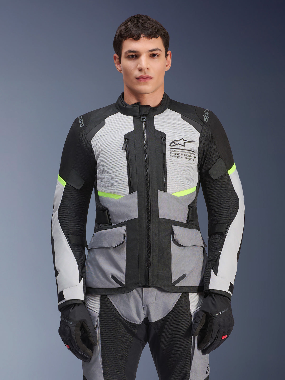 Alpinestars Andes Air Drystar-jacka, adventure touring-motorcykeljacka, Ice Gray och Dark Gray med svarta paneler och neongula detaljer, bärs med matchande byxor och handskar, med nätpaneler för ventilation och cargofickor