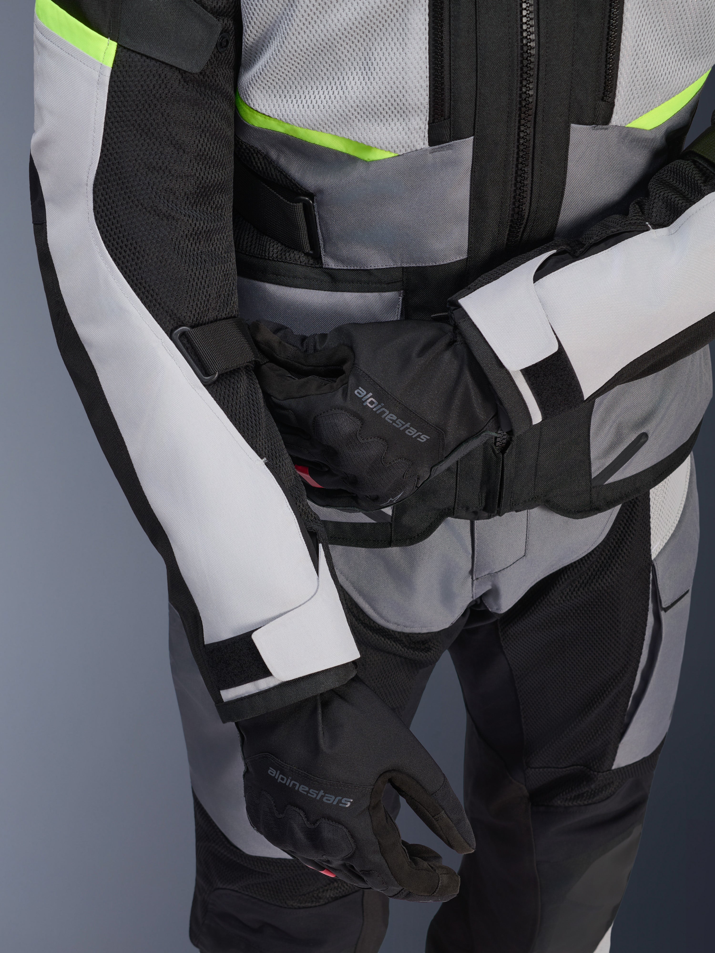 Alpinestars Andes Air Drystar® jacka, touringjacka för motorcykel, isgrå och mörkgrå med neongula detaljer, närbild som visar meshpaneler och justeringsremmar, bärs tillsammans med svarta Alpinestars-handskar