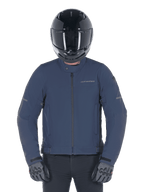Alpinestars Husker Waterproof Jacket, Night Navy, urban motorcykeljacka buren med en svart helhjälm och gråa handskar, med en teknisk softshell-utsida och diskret branding