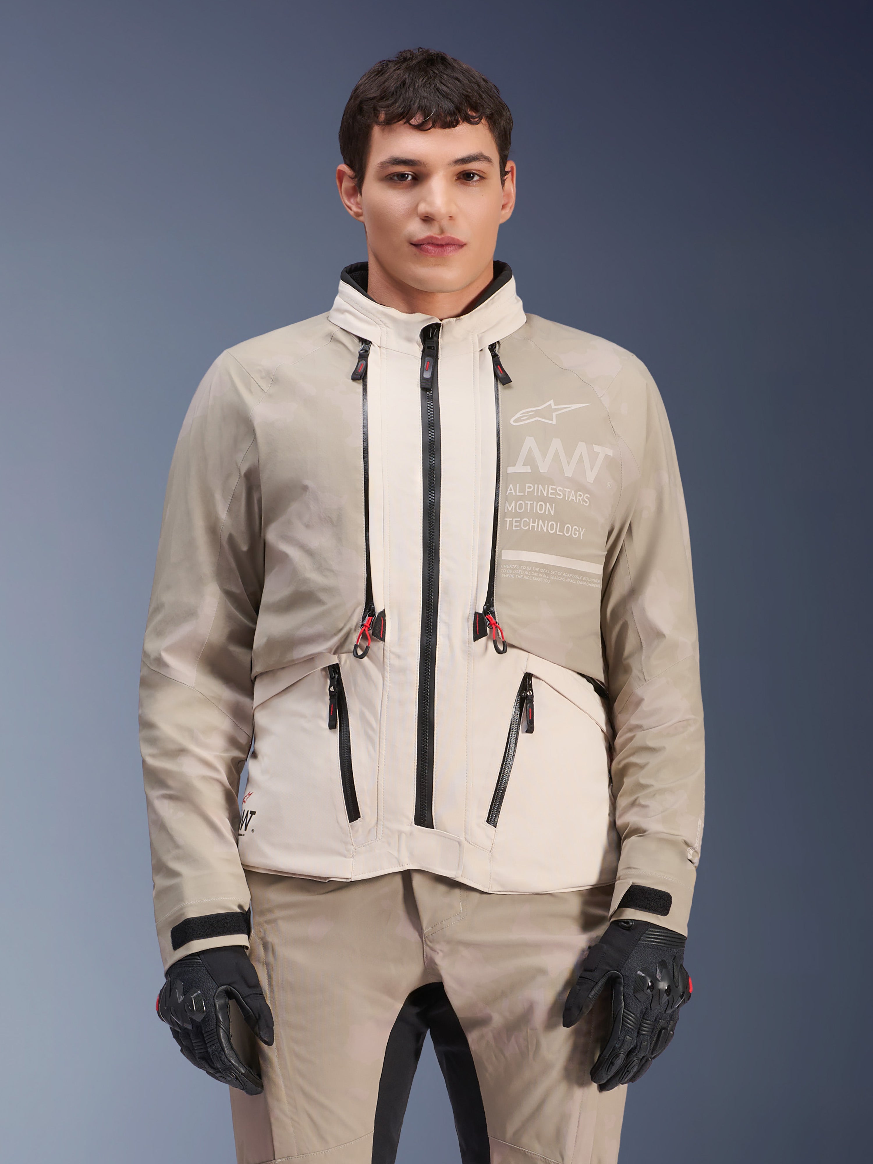 Alpinestars AMT-10LAB Drystar® XF-jacka, äventyrsmotorcykeljacka, White Sand Aluminum Camo, modulär design med svarta dragkedjor och röda detaljer, bärs med matchande byxor och svarta handskar, med Alpinestars Motion Technology-märkning på bröstet, professionellt körställ för alla väder