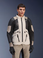Alpinestars AMT-10LAB Drystar® XF-jacka, White Sand Aluminum Camo, äventyrsjacka för motorcykel med svarta MATRYX®-meshpaneler och läderförstärkningar, bärs av en modell med svarta handskar och matchande sandfärgade byxor, studioporträtt