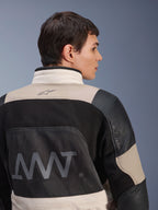 Alpinestars AMT-10LAB Drystar® XF-jacka, sedd bakifrån på manlig modell, färgkombinationen White Sand Aluminum Camo och svart, med stor AMT-logotyp, ventilationspaneler i mesh och läderförstärkningar, tekniska motorcykelkläder för äventyrskörning