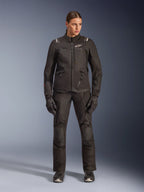 Kvinnlig förare i Alpinestars Stella Andes V4 Drystar®-jacka i svart, kombinerad med matchande svarta adventure-touringbyxor och handskar, teknisk textilkonstruktion med flera praktiska fickor och vit Alpinestars-logotyp, komplett motorcykelutrustning för alla väder