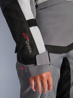 Alpinestars Stella Andes V4 Drystar mc-jacka för dam i grå textil, äventyrsmodell med ärmlogotyp och kardborre vid handleden.