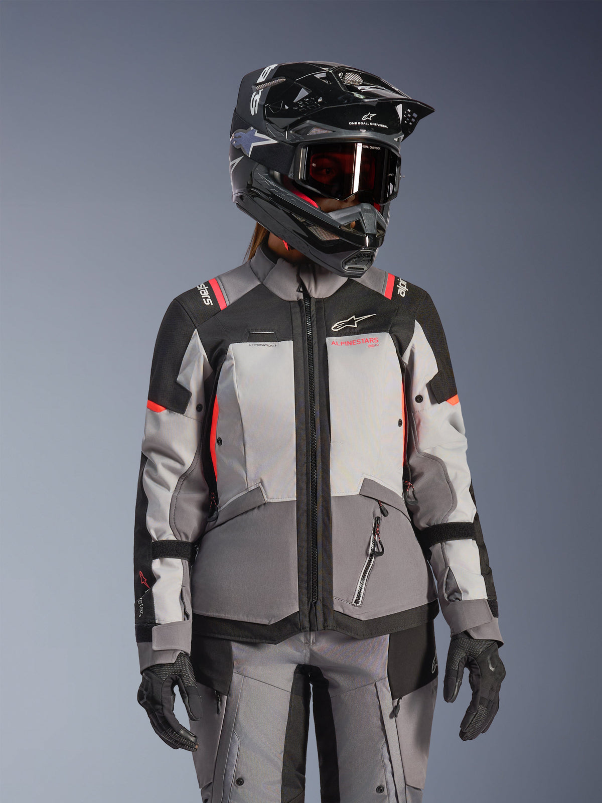 Alpinestars Stella Andes V4 Drystar damjacka, grå och svart med coral fluo, vattentät motorcykeljacka bärs av modell med hjälm.
