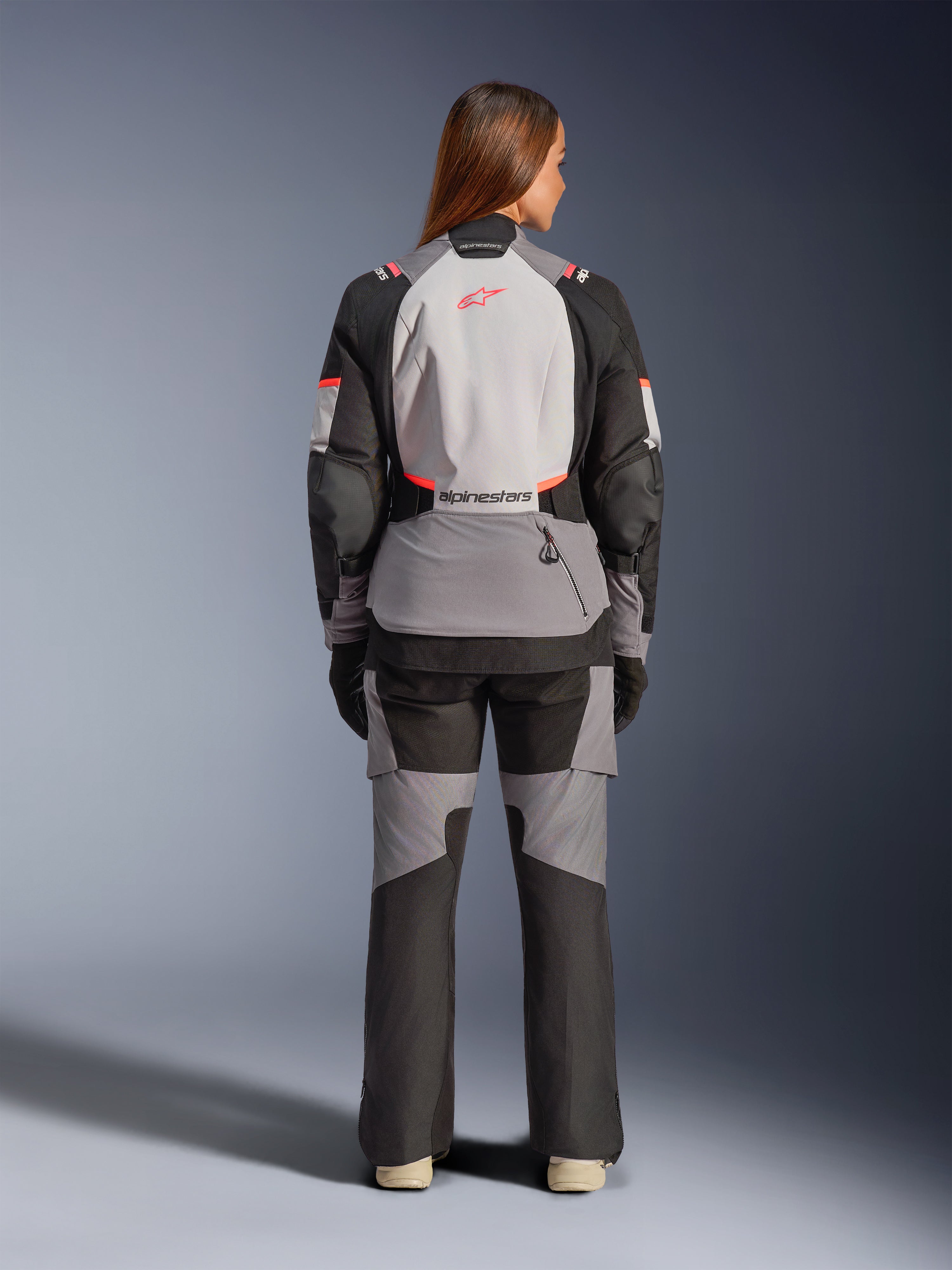 Alpinestars Stella Andes V4 Drystar jacka, vattentät MC-jacka för dam i grått och svart, äventyrstouring, modell sedd bakifrån i matchande utrustning, CE-certifierat skydd.