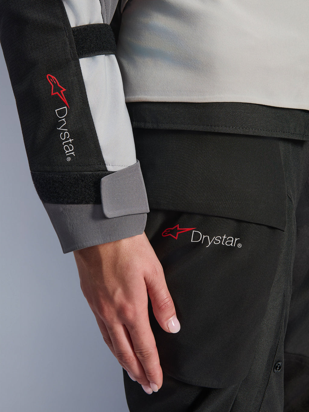 Närbild på detaljer av Alpinestars Stella Andes V4 Drystar® damjacka, ärm och matchande byxor, med Drystar-logotypen, isgrå och svart textilkonstruktion, vattentät märkning för äventyrstouring-utrustning